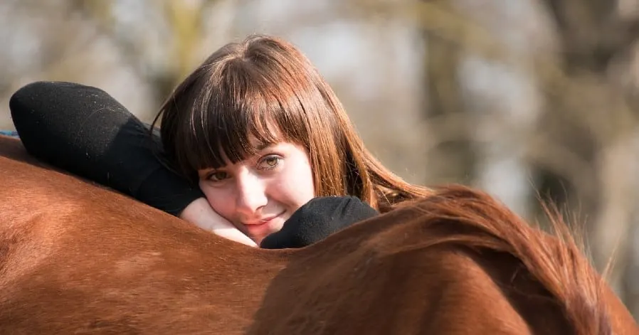 Girl resting and smiling on a horse's back