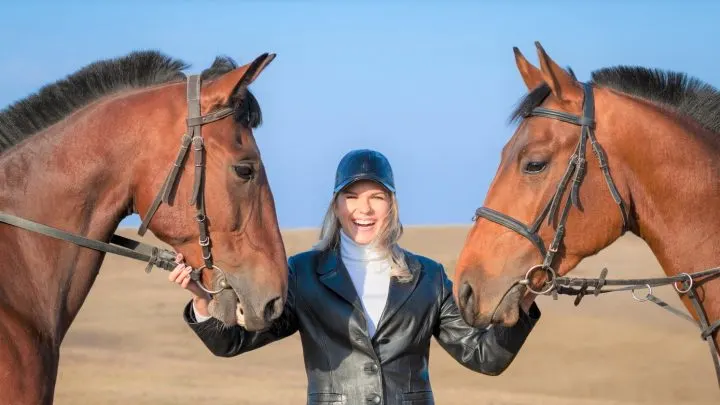 Woman holding two draft horses by the reins in a field