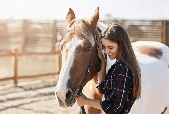 Young woman stroking her horse