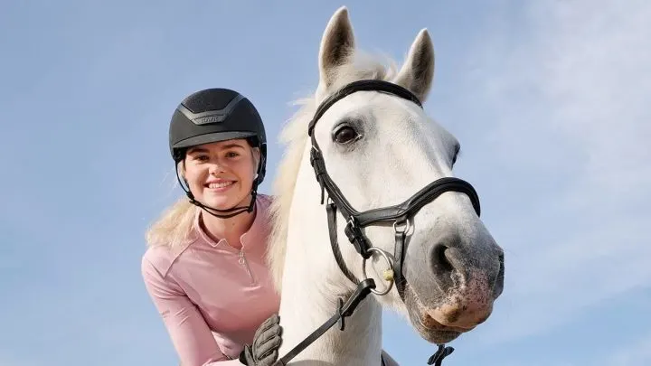 Esme Higgs riding a horse and smiling at the camera