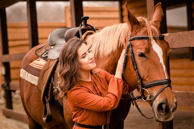 Girl smiling at a tacked up horse
