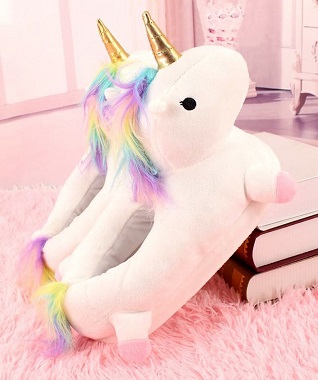 Plush unicorn slippers resting against a stack of books