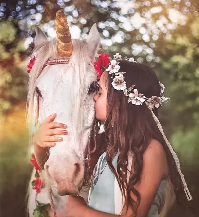 Young girl holding and kissing a unicorn