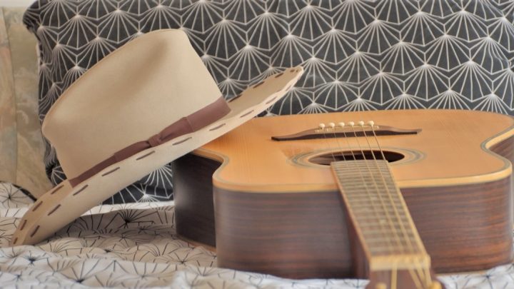 Cowboy hat on a bed with a guitar