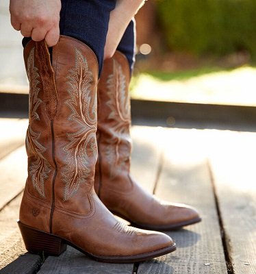 Woman putting on Ariat cowboy boots