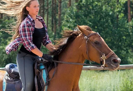 Girl riding a horse that has a hackamore bridle on