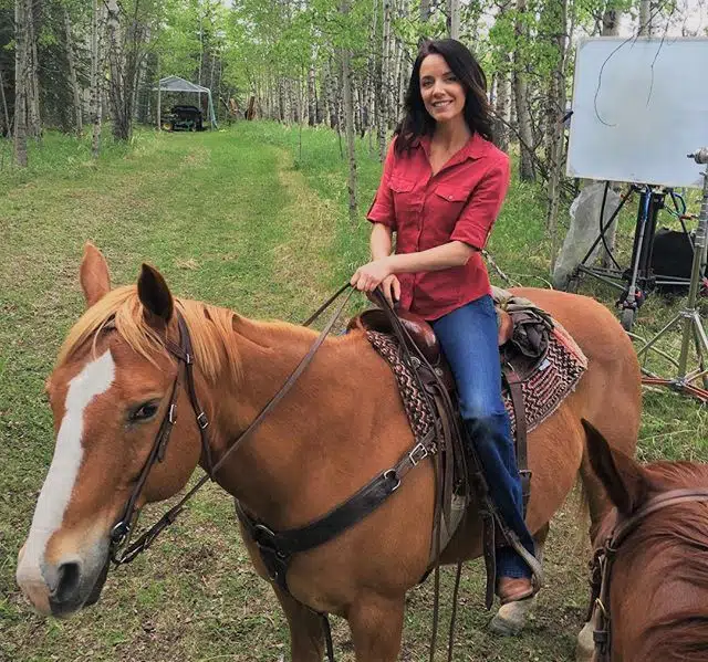 Michelle Morgan riding a horse on the Heartland set