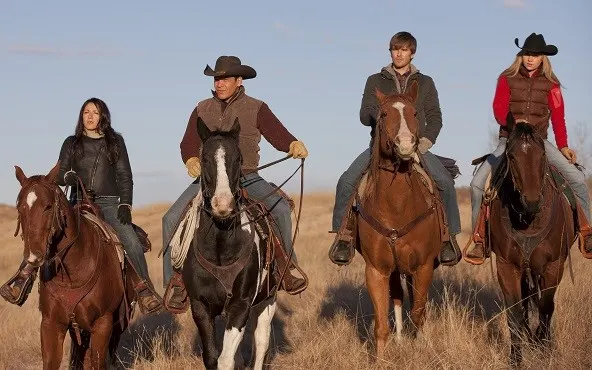 Four Heartland TV series characters riding horses