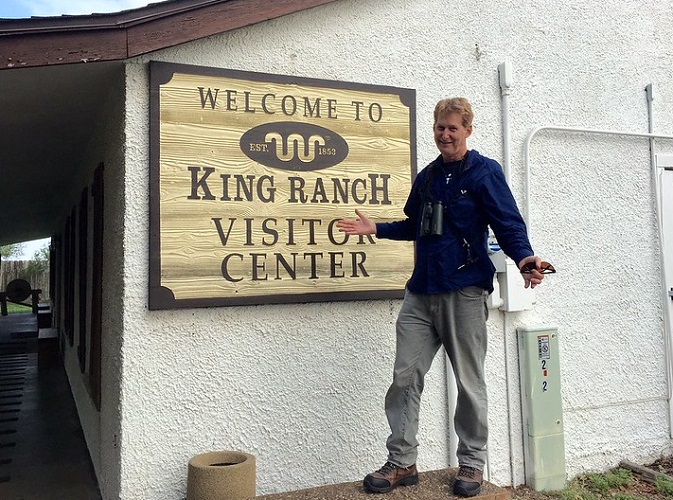 Man standing beside a King Ranch visitor center sign