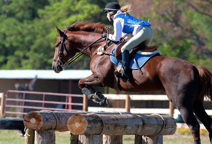 Teen rider jumps over an obstacle on a cross country course