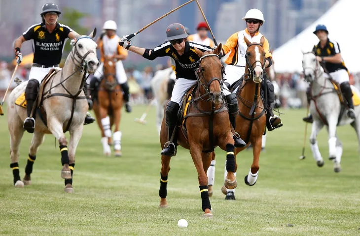 Woman about to hit the ball in a horse polo game