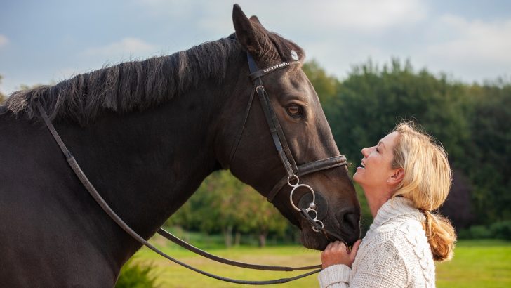 Woman holding her horse and smiling