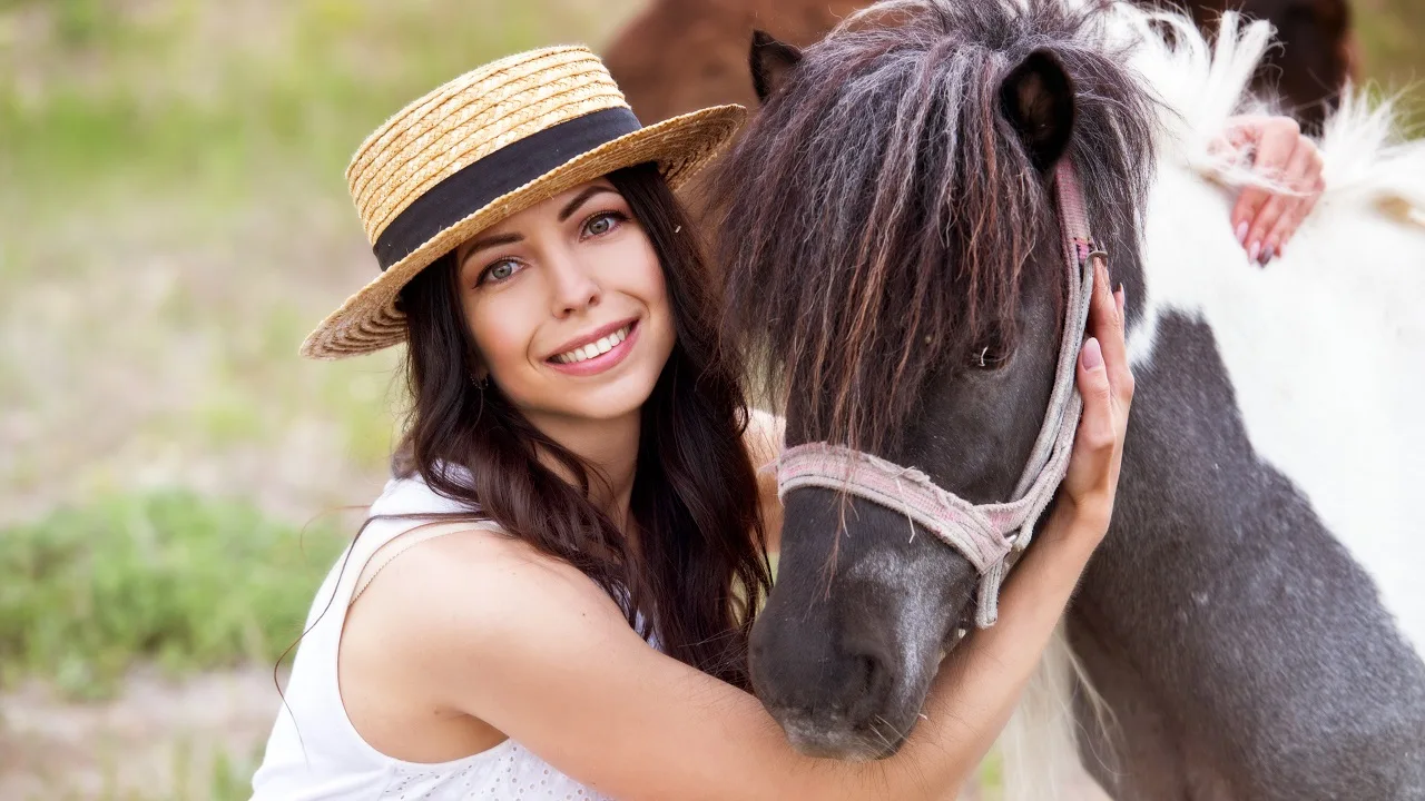 Woman smiling and looking at the camera while hugging a cute little pony