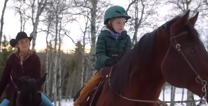 Amy Fleming and Lyndy Fleming riding horses in a snowy forest in Heartland season 16 episode 15