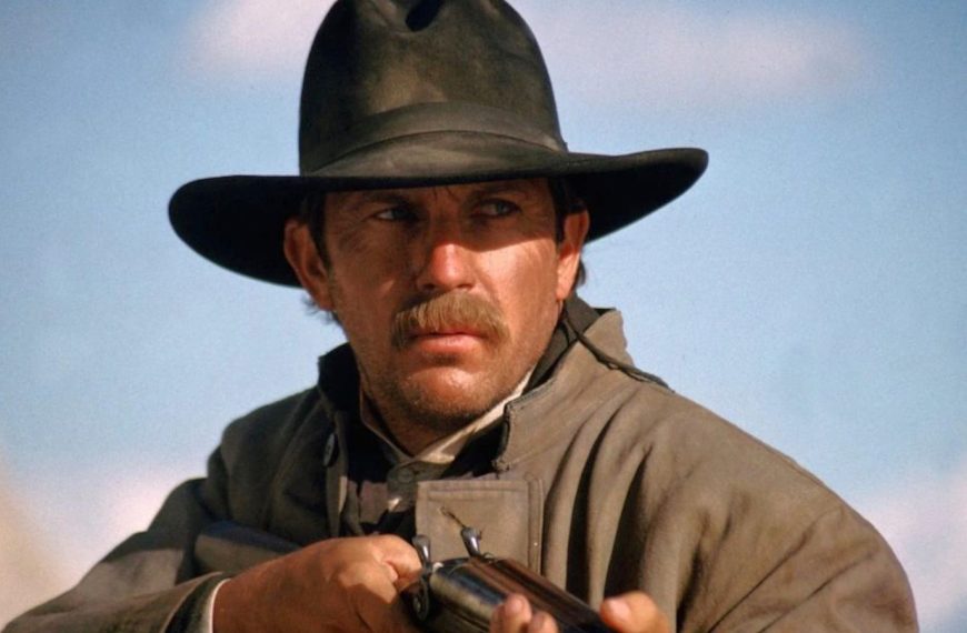 Close up of Kevin Costner in cowboy gear holding a shotgun in a western movie